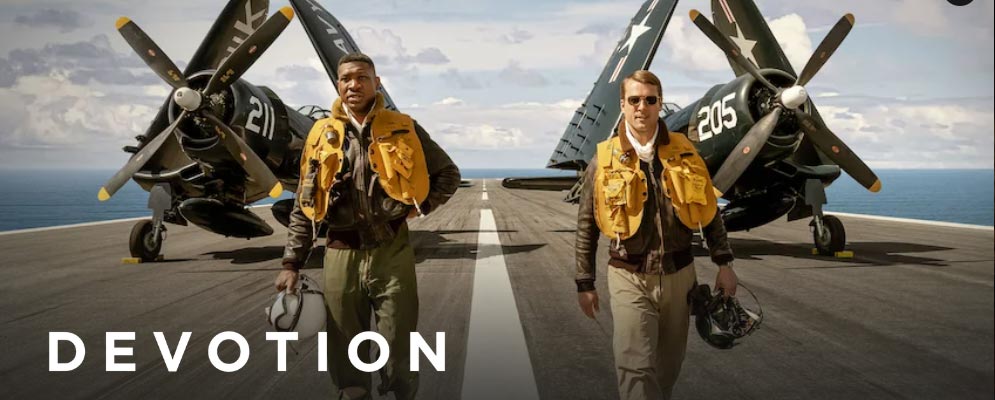 Screenshot of Devotion (film) with protagonists walking on an aircraft carrier in front of two warplanes. 